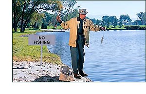 Man fishing next to 'no fishing' sign